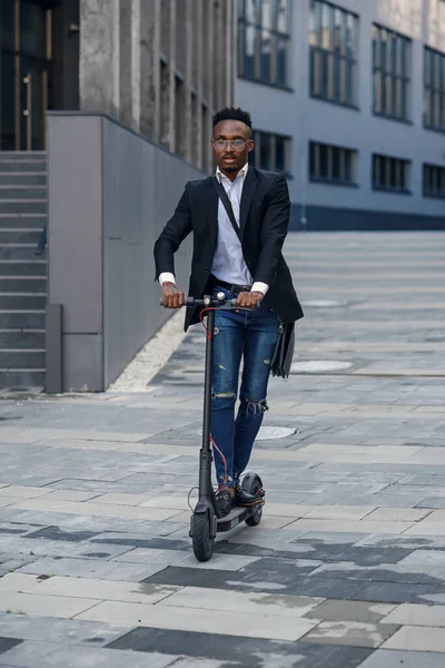 Современный афро-американский бизнесмен ездит на электрическом скутере после окончания рабочего дня в офисе. — стоковое фото