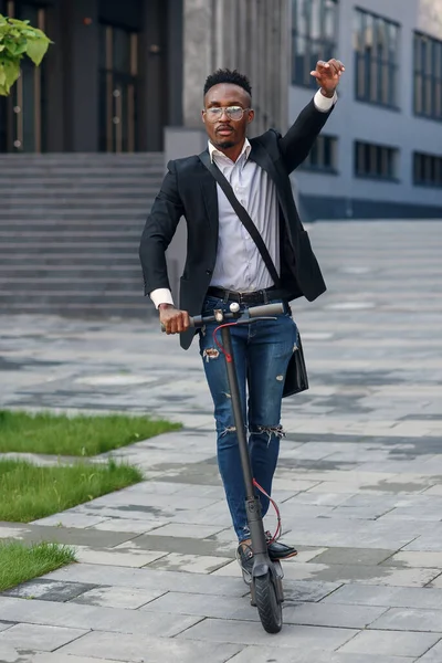 Moderno hombre de negocios de piel oscura monta scooter eléctrico después de terminar su día de trabajo en la oficina. — Foto de Stock