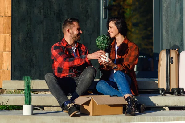 Young couple sitting on stairs having fun unpacking boxes after moving to new house. — Stock Photo, Image