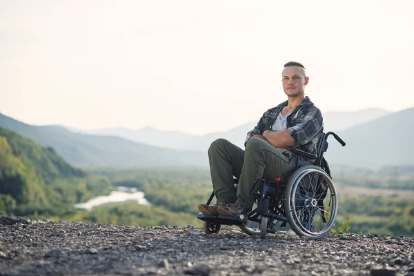 Портрет молодої вольової мотивованої людини в інвалідному візку, насолоджуючись красою природи в горах . — стокове фото