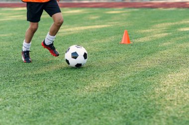 Futbolcu sahada topa vuruyor. Futbol oyuncuları antrenman yapıyor. Futbolcu ayaklarını çimenlerde tekmeleyip topa vuruyor..