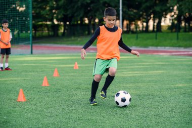 Futbolcu sahada topa vuruyor. Futbol oyuncuları antrenman yapıyor. Genç futbolcu yeşil çimlerde topa vuruyor.