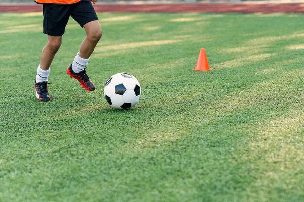 Fußballer, der Ball auf dem Feld kickt. Fußballer beim Training. Nahaufnahme Fußballer Füße kicken Ball auf Gras. — Stockfoto