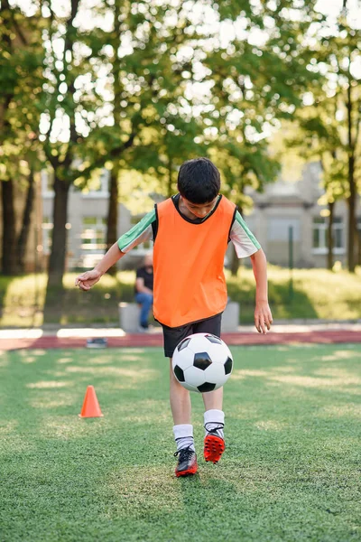 Motivovaný mladý fotbalista nacpe fotbalový míček na nohu. Cvičení sportovních cvičení na umělém stadionu. — Stock fotografie