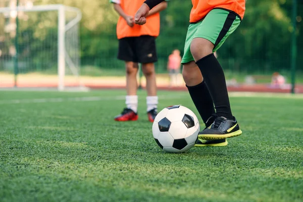 Soccer player kicking ball on field. Soccer players on training session. Close up footballer feet kicking ball on grass.