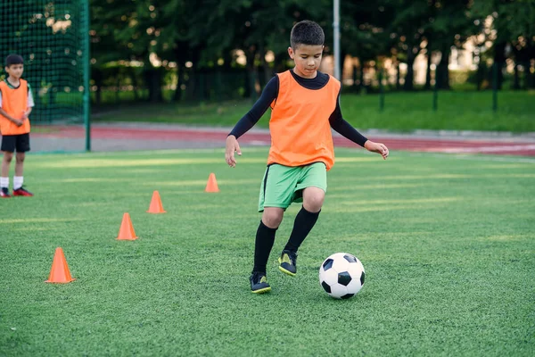 Soccer player kicking ball on field. Soccer players on training session. Teen footballer kicking ball on green grass.