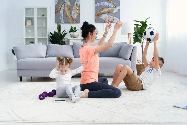Sports mom with son doing morning work-out at home. Mum and son do exercises together, healthy family lifestyle concept
