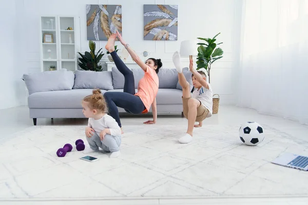 Sports mom with son doing morning work-out at home. Mum and son do exercises together, healthy family lifestyle concept