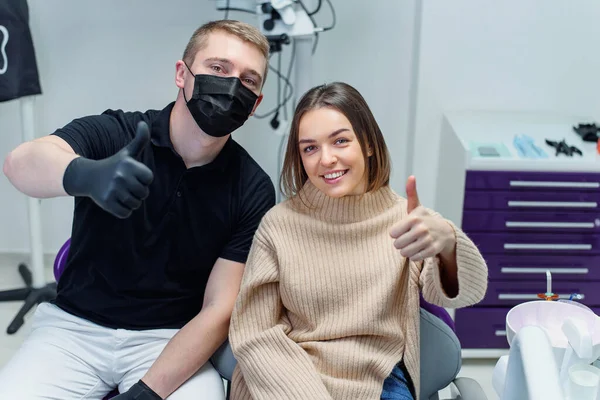 Paciente do sexo feminino satisfeito e dentista qualificado mostram sinal ok após tratamento dentário profissional na clínica odontológica. — Fotografia de Stock