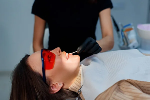 O dentista usa um cotonete para lubrificar os lábios da paciente, para facilitar a percepção de outros procedimentos.. — Fotografia de Stock