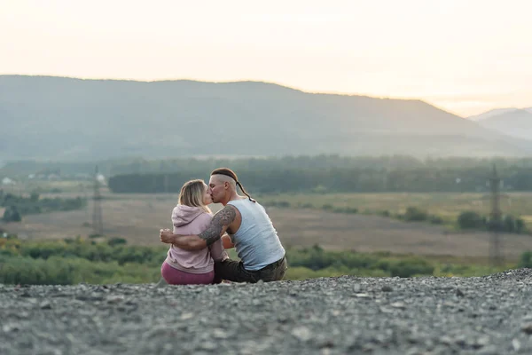 Giovane uomo abbraccia la sua ragazza sulla vetta della montagna al tramonto sfondo. — Foto Stock
