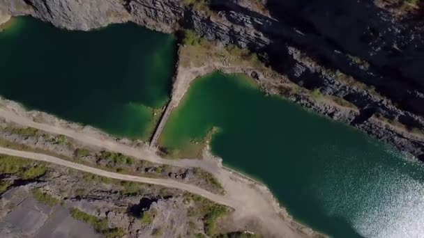 Voo de círculo sobre um desfiladeiro de pedra de uma antiga pedreira com belo lago azul-turquesa com ponte no meio. — Vídeo de Stock