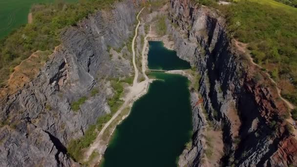 Vola attraverso un canyon di pietra di una vecchia cava con lago turchese e un piccolo ponte. Velka Amerika Repubblica Ceca. — Video Stock