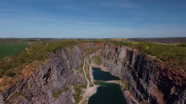 Fliegen Sie durch eine steinerne Schlucht eines alten Steinbruchs mit türkisfarbenem See und einer kleinen Brücke. Velka Amerika Tschechische Republik. — Stockvideo