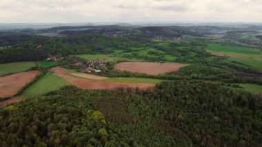 Hilly Valley Panoraması. Yeşil tepelerin eteklerinde tarlaları olan yüksek dağlı bir köy..
