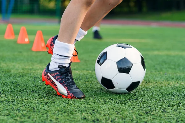 Soccer player kicking ball on field. Soccer players on training session. Close up footballer feet kicking ball on grass.