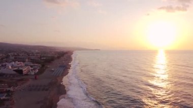 Bir İHA gün doğumunda Ege Denizi sahilinde adanın üzerinde uçar..