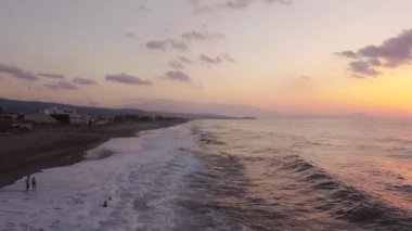 Bir İHA gün doğumunda Ege Denizi sahilinde adanın üzerinde uçar..