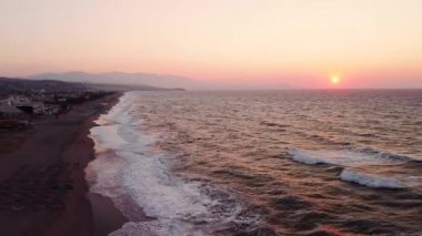 Bir İHA gün doğumunda Ege Denizi sahilinde adanın üzerinde uçar..