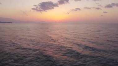Bir İHA gün doğumunda Ege Denizi sahilinde adanın üzerinde uçar..