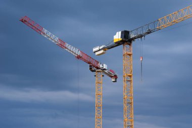 Gün batımında gökyüzünün arka planında iki vinç var. Yeni konut kompleksinin inşaatı.