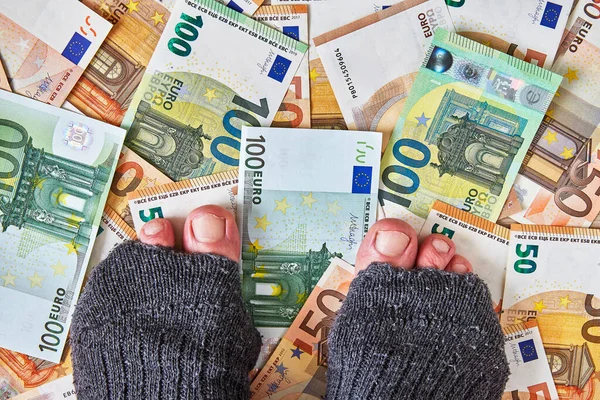 Fötter i trasiga holey strumpor på euro pengar — Stockfoto