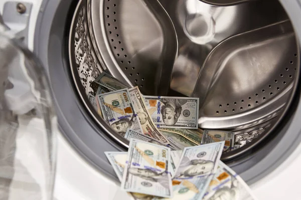 money dollar banknotes in the opening washing machine - financial crime concept