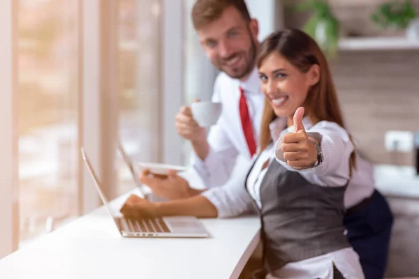 Gyönyörű üzleti dolgozók dolgoznak együtt a laptop az irodában csinál boldog hüvelykujj fel gesztus kézzel. — Stock Fotó
