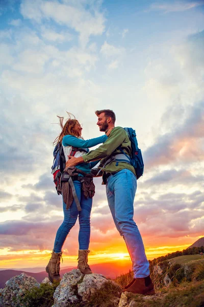 Par på toppen av ett berg kramas och njuta av utsikten. — Stockfoto