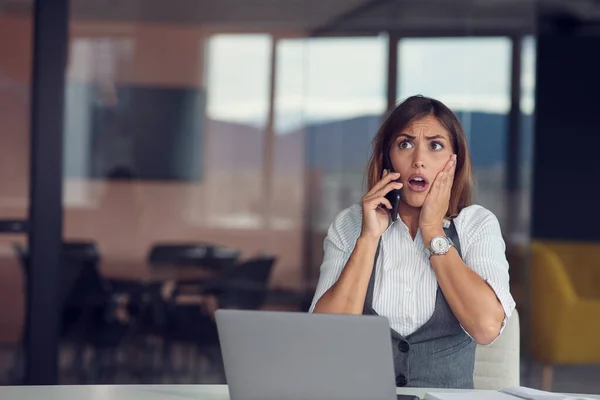 Angry business woman on the phone in modern office
