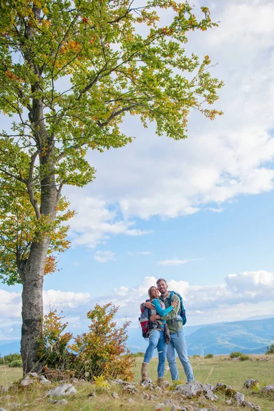 Happy couple hiking and enjoying a valley view and hugging — Stock Photo, Image