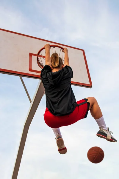 Samice hrají basketbal na pouličním hřišti. Žena streetball hráč dělat slam ponořit do basketbalové hry. — Stock fotografie