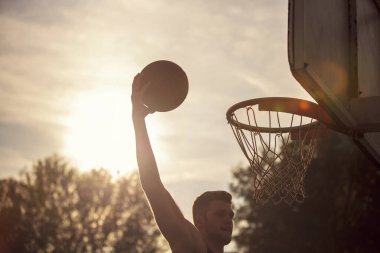 Genç adam zıplayıp smaç basıyor. Sokak basketbolu, basketbol oynuyor. Şehir otantik.