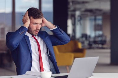 Bitkin hissediyorum. Hüsrana uğramış genç sakallı adam ofisinde çalışırken gözlerini kapalı tutuyor.