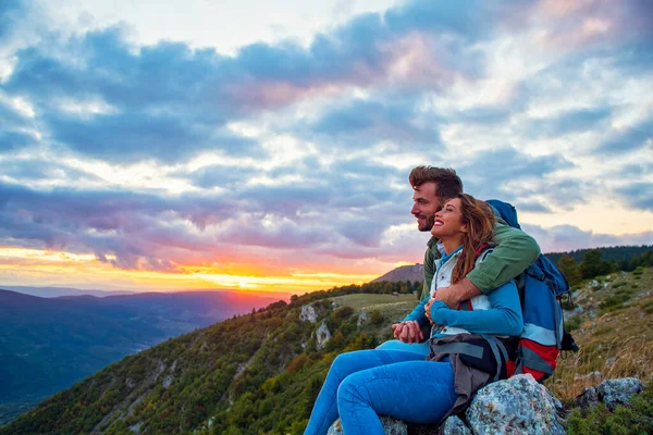 Casal jovem sentado no topo da montanha — Fotografia de Stock