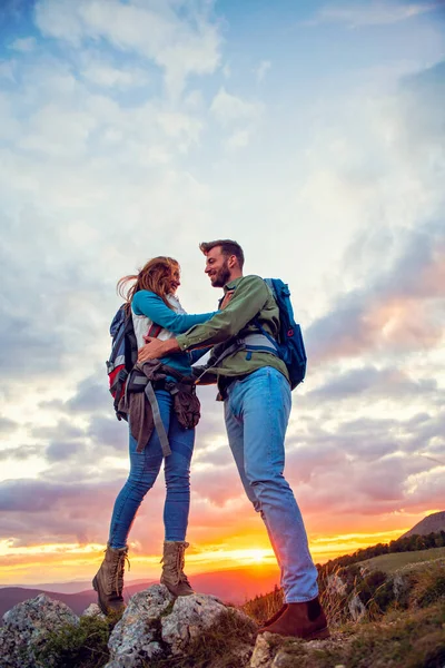 Pareja en la cima de una montaña Abrazando y disfrutando de la vista. — Foto de Stock