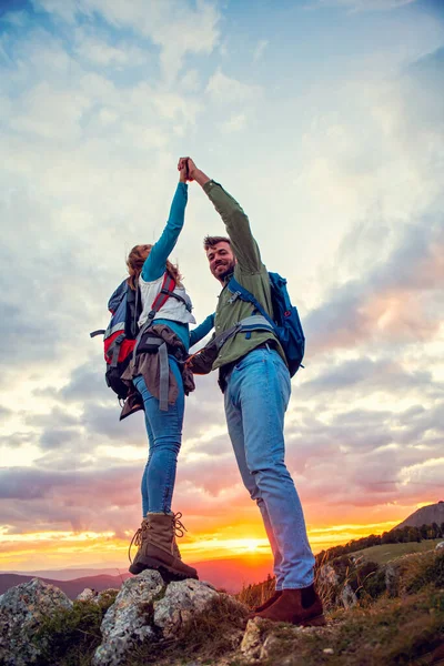Paar op de top van een berg schudden opgeheven handen — Stockfoto
