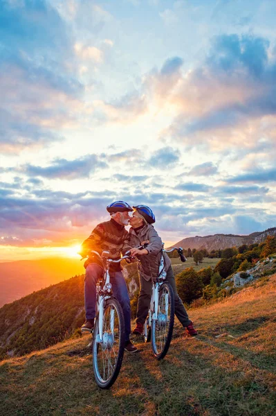 Pareja mayor activa en un paseo en bicicleta country. Besándose en su descanso. —  Fotos de Stock