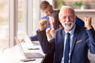 Üst düzey yönetici arka planda genç dilleri olan bir dizüstü bilgisayar kullanıyor.