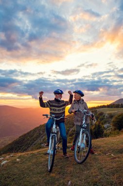 Parkta bisiklet süren ve el kaldıran mutlu yaşlı çift.