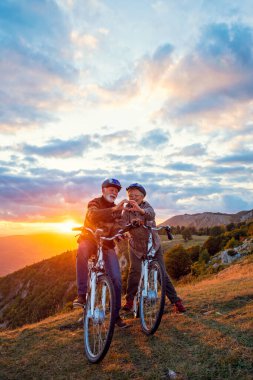 Bisikletli aktif kıdemli çift elleriyle kalp şekillendiriyor ve öpüşüyor..