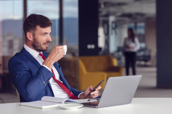 Dia casual no escritório. Sorrindo masculino empregado usando laptop e beber café. — Fotografia de Stock