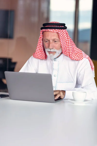 Empresário árabe confiante e sorrindo no escritório usando laptop. — Fotografia de Stock