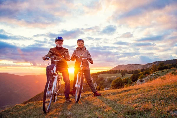 Active seniors having walk with bike in autumn nature. They having romantic time outdoor. — Stock Photo, Image