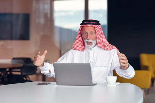 Hombre de negocios árabe se ve sorprendido mientras usa un ordenador portátil — Foto de Stock