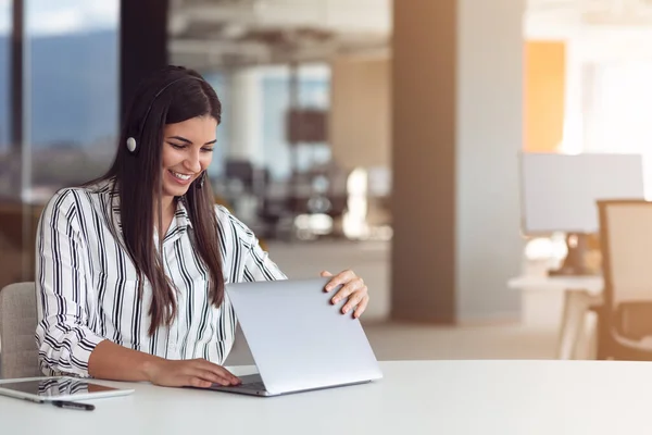 Portret kobiety skupionej w słuchawkach biorącej udział w webinarium w biurze — Zdjęcie stockowe