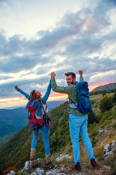 Couple au sommet d'une montagne serrant les mains levées — Photo