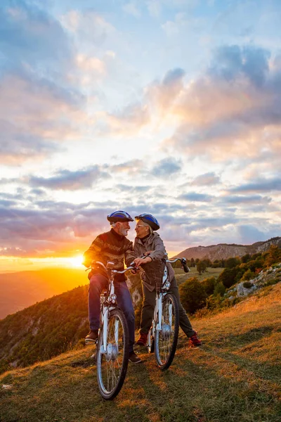 Pareja mayor activa en un paseo en bicicleta country. Besándose en su descanso. —  Fotos de Stock