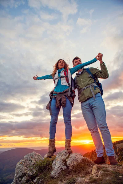 Couple au sommet d'une montagne serrant les mains levées — Photo