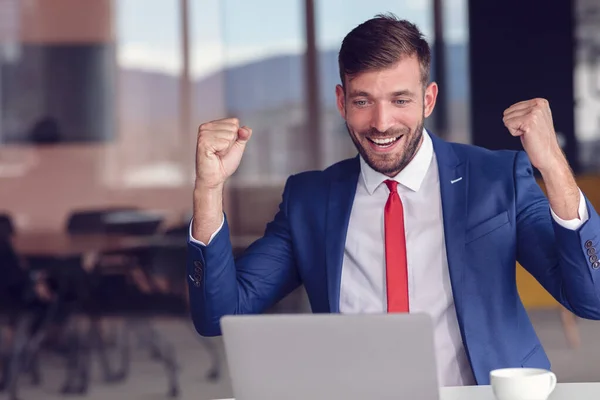 Casual businessman celebrating success at modern office.